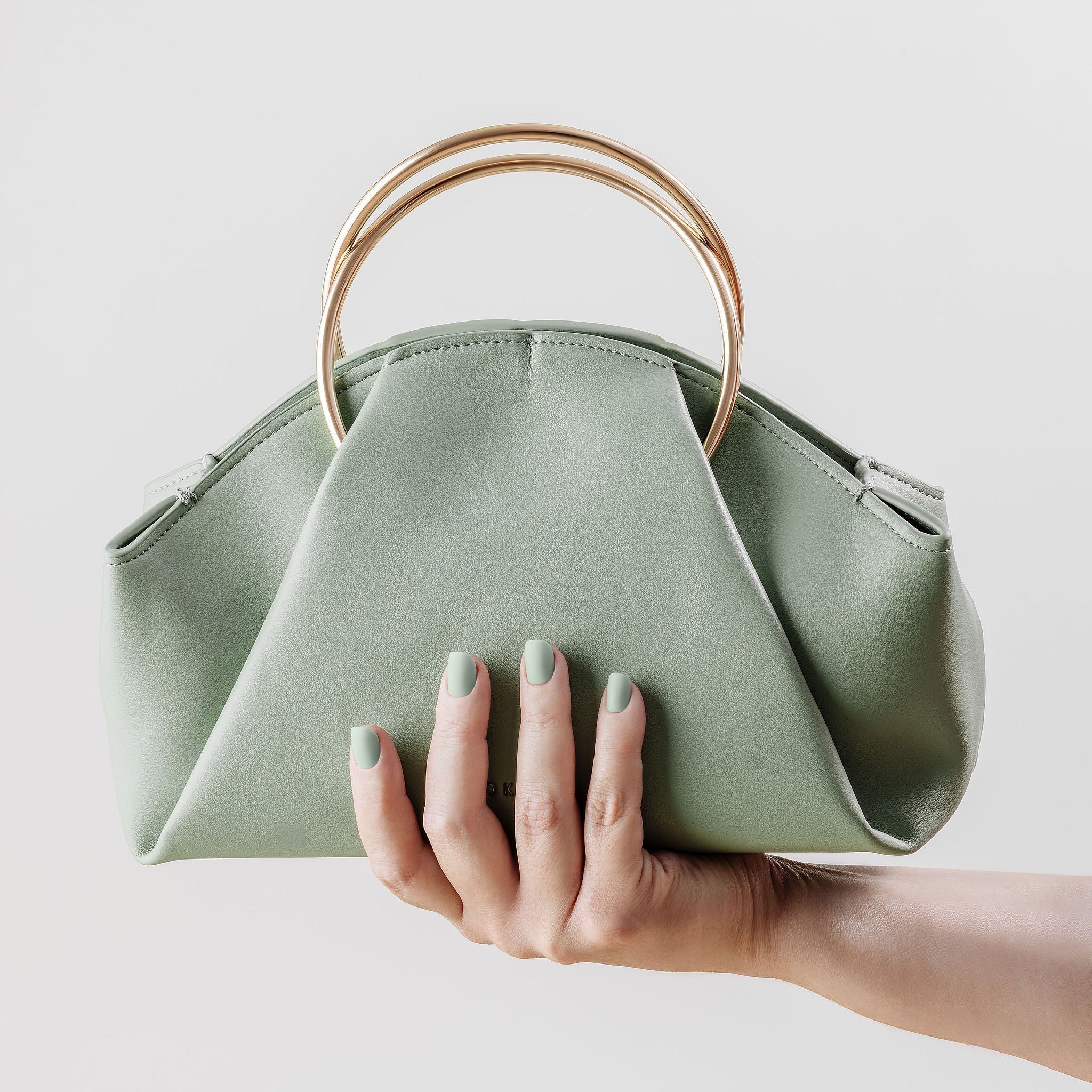 Green manicure - Hand holding a light green handbag